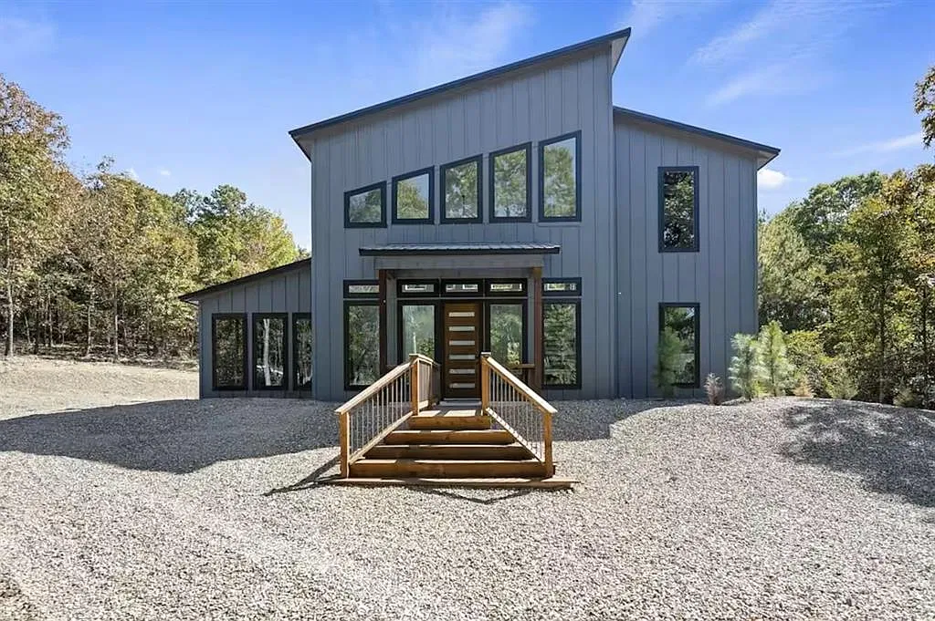 Front of Champagne Pines, a modern dark cabin with tall windows set among trees near Broken Bow, Oklahoma
